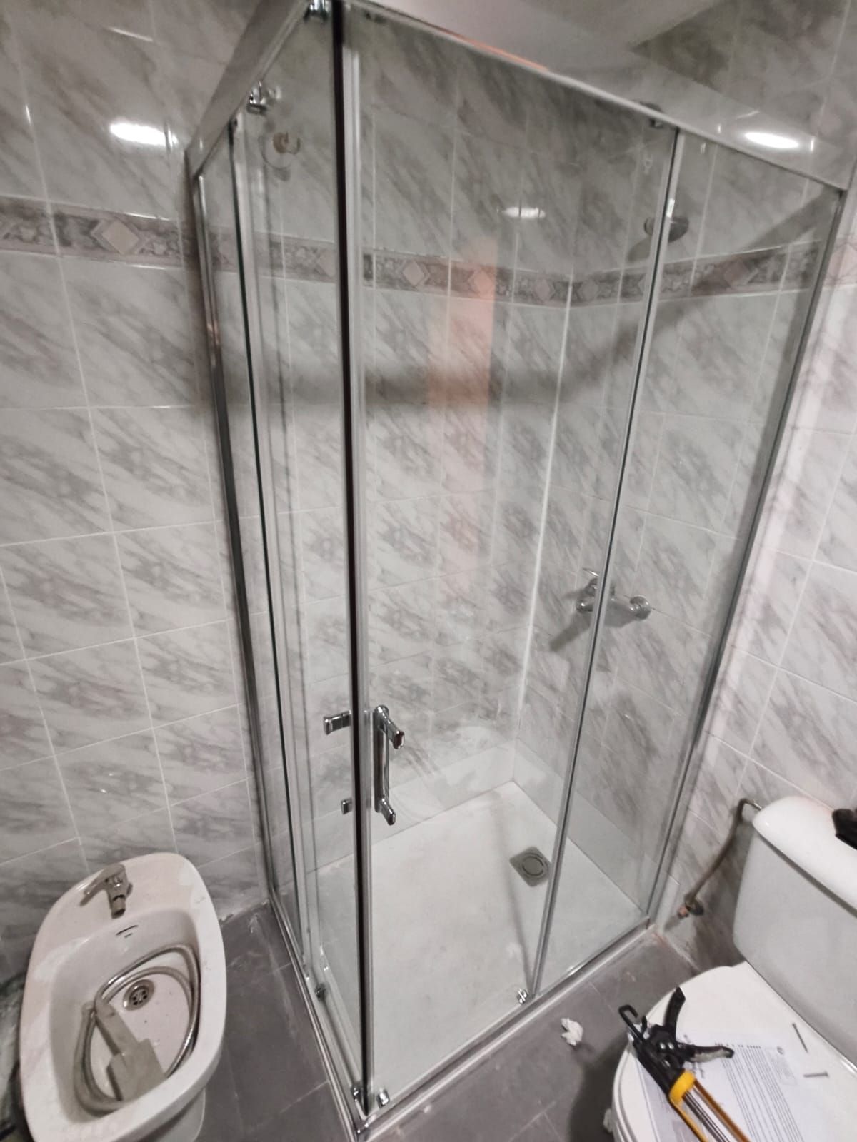 Baño reformado con mampara de cristal y alicatado gris en Albacete, obra de DCELITE